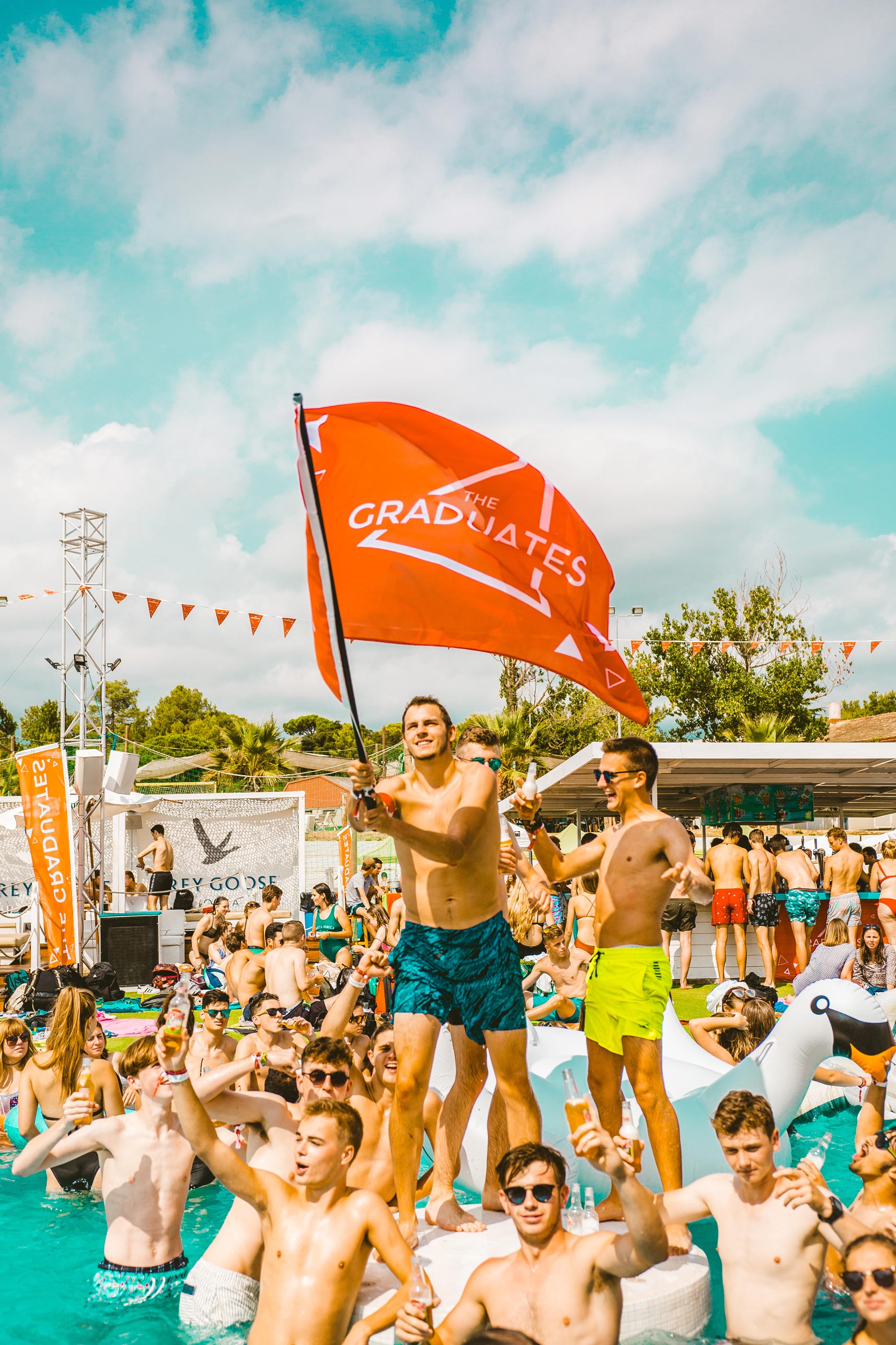 Student in pool waving The Graduates flag